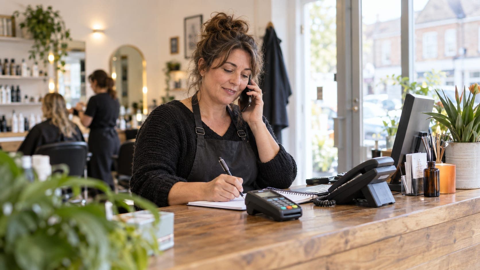Salon owner making a call beside a card terminal and desk phone